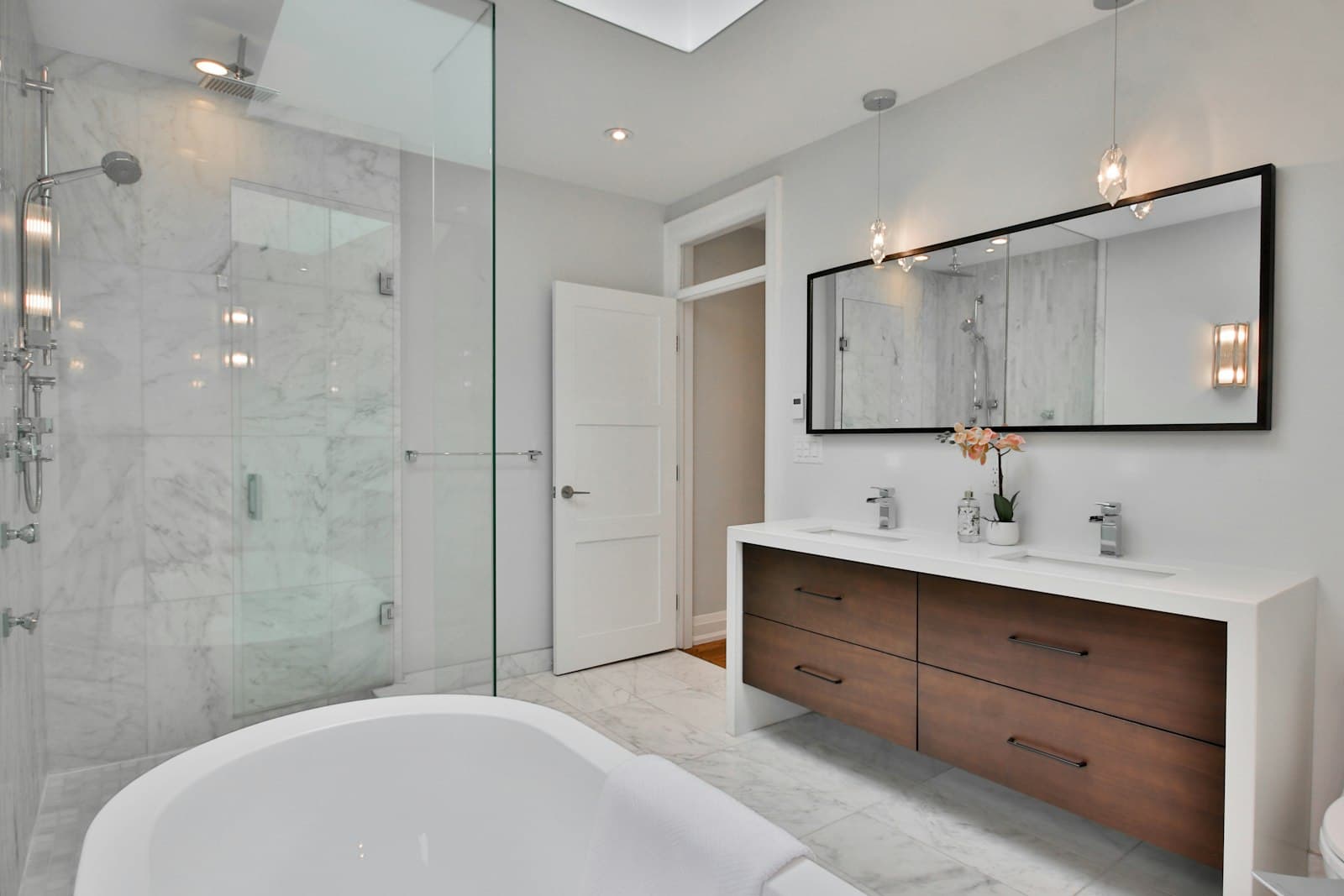 Bagno padronale in marmo con doppio lavabo, box doccia walk-in e vasca freestanding.