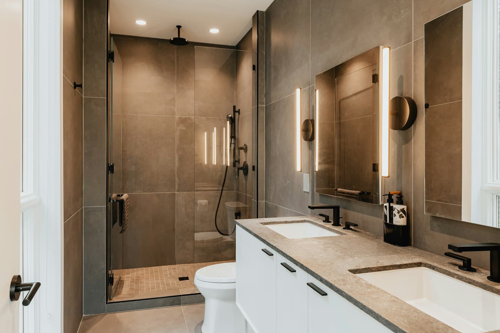 Bagno dai toni caldi con doccia walk-in, piatto a filo pavimento e illuminazione a binario.